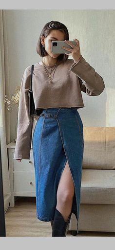 a woman taking a selfie in front of a mirror wearing a skirt and sweater