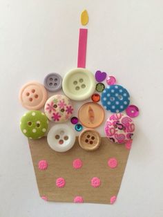 a cupcake decorated with buttons and a candle