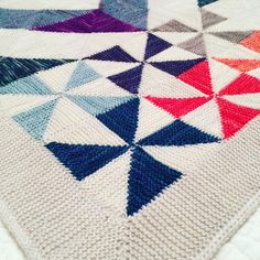 a crocheted blanket with many different colored triangles on the bottom and one in the middle