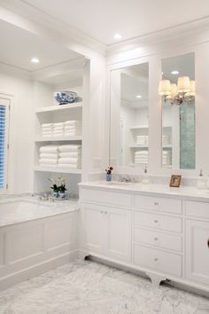 a large bathroom with white cabinets and marble counter tops