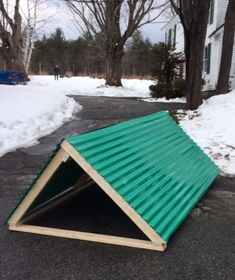 a green metal roof sitting on the side of a road next to snow covered trees