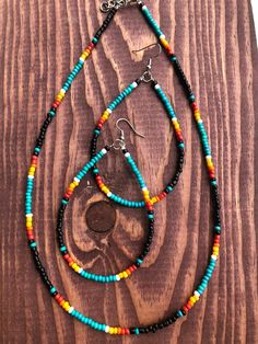 two necklaces with multi colored beads on a wooden surface