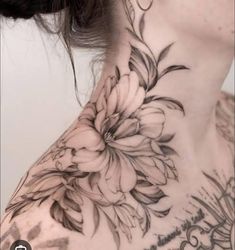 a woman's neck with flowers on it and the back of her neck is covered in black ink