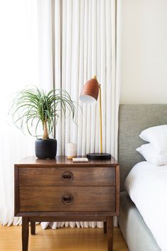 a nightstand with a lamp and a plant on it