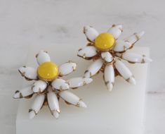 These stunning vintage clip-on earrings are from the renowned Beau Jewels company. These statement earrings feature a beautiful yellow and white flower. Beau Jewels was a popular costume jewelry company that produced high-quality pieces from the 1940s to 1970s. Their designs were known for their intricate details and use of colorful stones. These earrings are a perfect example of the exquisite craftsmanship that Beau Jewels was known for. Don't miss your chance to own a piece of fashion history! The earrings measure 1 1/8 inch. oooooooooo HAVE QUESTIONS? Please convo me, I'm more than happy to answer any questions you may have. S A T I S F A C T I O N Guaranteed! If for any reason you don't love your purchase, please send it back for a full refund! Retro White Flower Jewelry, White Clip-on Flower Earrings, White Flower Clip-on Earrings, Yellow Flower-shaped Retro Jewelry, Retro Yellow Flower Jewelry, Retro Yellow Flower-shaped Jewelry, Vintage White Clip-on Earrings For Wedding, Vintage Clip-on Flower Earrings, Handmade Vintage White Clip-on Earrings