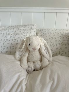 a white stuffed rabbit sitting on top of a bed