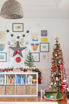 a living room decorated for christmas with pictures on the wall and tree in front of it