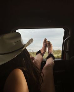 a woman sitting in the back seat of a car with her feet up on the window sill