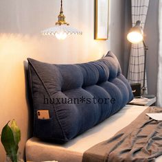 a blue pillow sitting on top of a bed next to a lamp