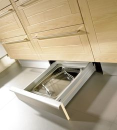 an open dishwasher drawer in the middle of a kitchen floor with wooden cabinets