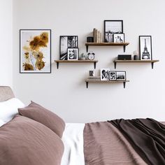 a bed with two shelves above it and pictures on the wall next to each other