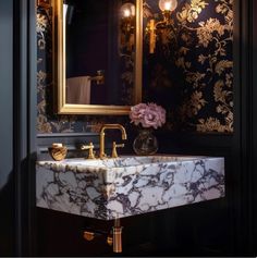 a bathroom sink sitting under a mirror next to a wall mounted faucet with flowers on it