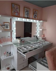 a vanity with lighted lights and drawers in a pink room next to a mirror on the wall