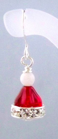 a pair of red and white earrings hanging from a silver earring hook on a string