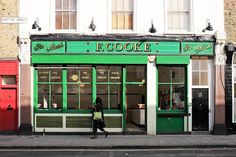 a woman walking past a green store front