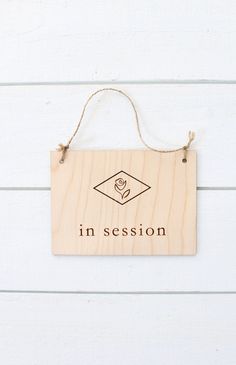 a wooden sign hanging on the side of a wall that says in session with a diamond