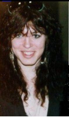 an old photo of a woman with sunglasses on her head and long curly hair smiling at the camera