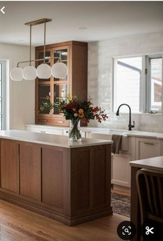 a kitchen with wooden cabinets and an island in front of a window that has flowers on it