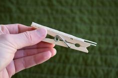 a person holding a pair of scissors in their left hand and another piece of wood on the other