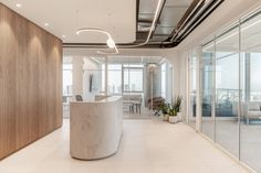 an office with large white counter and glass doors on the walls, along with potted plants