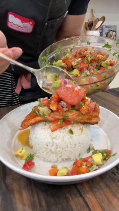 a person is holding a spoon over a plate with rice and vegetables on it,