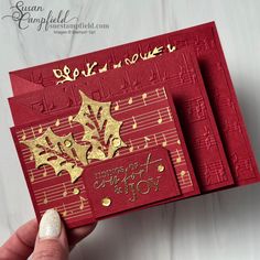 two red cards with gold foil designs on them, one is folded and the other has music notes