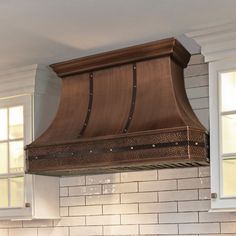 a stove top oven mounted to the side of a kitchen wall with two windows above it