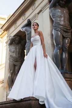 a woman in a white dress standing next to statues