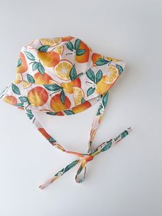 "Handmade brimmed orange print with soft pink background sun hat Breathable 100% cotton fabric Cotton lining | satin lining Measurements: Tie length for all - 16\" / 30-31 cm 0-3 months - 13\" / 33cm 3-6 months - 15\" / 38 cm 6-12 months - 17\" / 43cm 12-24 months - 18.5\" / 46-48 cm 2-4 years - 20\" / 50 cm 4-7 years - 20.5\" / 52 cm 7-12 years - 21.5\" / 54 cm Adult Small - 22\"/56 cm Adult Medium - 23\"/58 cm Adult Large - 24\"/60 cm Care instructions: Machine wash in cold water, gentle dry, Adjustable Orange Sun Hat For Summer, Adjustable Summer Sun Hat In Orange, Summer Orange Adjustable Sun Hat, Adjustable Orange Summer Sun Hat, Orange Adjustable Summer Hat, Adjustable Orange Summer Hat, Orange Beach Sun Hat, One Size Fits Most, Pink Cotton Sun Hat With Uv Protection, Orange Brimmed Sun Hat For Summer