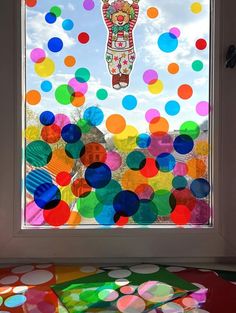 there is a window with many different colored balls on it and a teddy bear in the middle