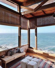 a living room filled with furniture and large windows overlooking the ocean in front of it