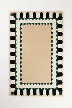 an area rug with black, white and green designs on the bottom in front of a wall