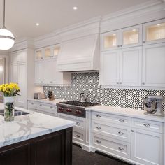 a large kitchen with white cabinets and marble counter tops, along with a center island