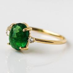 An emerald ring for the ages! This absolutely stunning ring from Charlie and Marcelle features an insanely gorgeous faceted natural emerald stone, flanked by two shimmering diamonds for good measure. Alternative engagement ring, or sumptuous gift to mark a milestone, this ring is an heirloom to treasure forever. To cus Emerald Ring With Diamonds, Oval Emerald Ring, Flower Diamond Ring, Silver Emerald Ring, May Birthstone Rings, Quartz Engagement Ring, Green Gemstone Ring, Stackable Wedding Bands, Sterling Silver Wedding Band