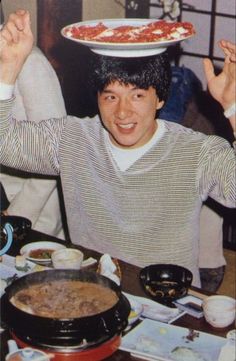 a man sitting at a table with a pizza on top of his head