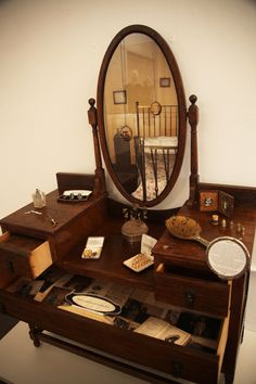 an antique desk with a mirror and other items on the top shelf in front of it