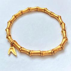 Bamboo Bracelet Gold 24K Plated Lucky Wealth Prosperity 🎋 Bracelet Approx. size: 6.5 🎋 Stretch Elastic Bracelet  🎋 Bamboo 24K Gold Plated Beads (7mm x 4mm) Each bead has a money coin symbol. 🎋 24K Gold Plated Spacer Beads and Bamboo Leaf Charm  📷 Check out our instagram @little.rainbow.factory for more pictures/videos of this item Photos were taken in natural sunlight. Please keep in mind that colors may vary from the photos taken due to the settings on your phone or monitor display and surface. *Please note that jewelry may tarnish due to oxidization* Adjustable Symbolic Gold Beaded Bracelets, Gold Bangle Stretch Bracelet, Gold Hand-strung Stretch Bracelet As Gift, Symbolic Gold Bangle Bracelet, Gold Hand-strung Round Charm Bracelet, Gold Hand-strung Charm Bracelet, Symbolic Gold Beaded Bracelets As Gift, Symbolic Gold Beaded Bracelets For Gifts, Gold Beaded Good Luck Bracelets