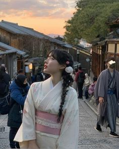 a woman dressed in traditional japanese clothing walking down the street