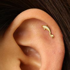 a close up of a person's ear with a small gold fish on it