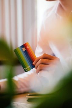 a person holding a credit card in their left hand while sitting at a table with plants