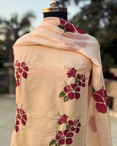 a dress with red flowers on it and a white shawl draped over the top