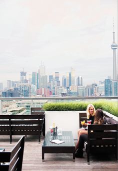 two women sitting on benches in front of a city skyline