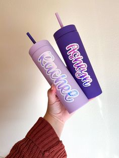 two purple tumblers with the words awesomeness on them are held up by a woman's hand