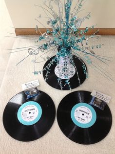 two black records sitting on top of a white carpet next to a vase with blue flowers