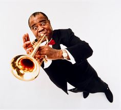 a man in a tuxedo is holding a trumpet and posing for the camera