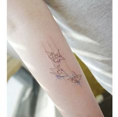 a woman with a tattoo on her arm that has an origami paper airplane