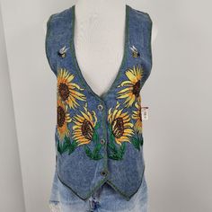 a denim vest with sunflowers painted on the front and back, sitting on a mannequin head