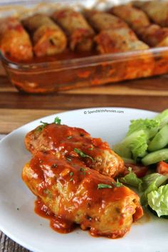 a white plate topped with meat covered in marinara sauce and veggies next to a casserole