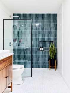 a bathroom with a toilet, sink and glass shower stall in the middle of it