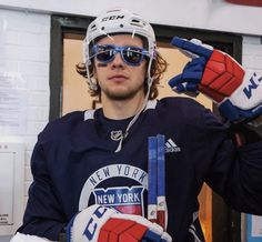 a hockey player wearing sunglasses and holding his hands up in front of him with the new york rangers logo on it